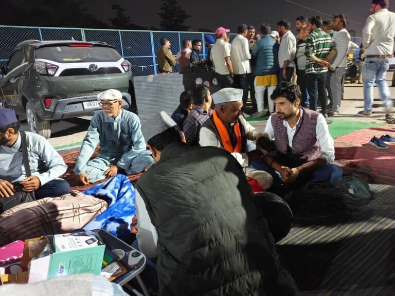 मुनि की रेती खारा स्रोत में शराब ठेके के विरोध में बैठे प्रदर्शनकारी, मौके पर मौजूद पुलिस और आबकारी टीम